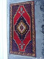 Full top view of the small Persian rug with central diamond medallion in red, black and yellow