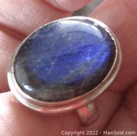 Close-up view of the oval labradorite stone showing blue luminescence and polished surface.