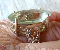 Close up side view of ring showing detailed openwork gallery design in sterling silver and large faceted light green oval quartz stone.