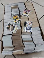 Large stacks of approximately 4000 hockey cards arranged on the floor, including cards showing players from Boston Bruins and Tampa Bay Lightning.