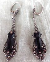 Clear image of the front side of both earrings showing black onyx stones and marcasite decorations in silver settings.