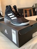 Front and side view of Adidas Pro Spark 2018 black and white basketball shoe on black Adidas box showing label with model BB7538 and size 11.5.