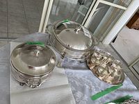 Full lot displayed on table, showing two silver plate chafing dishes with lids, one with heater and snuffer, and six tea cups on metal tray.