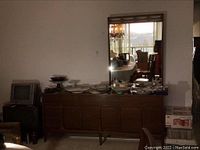 Front view of walnut finish dresser with mirror against wall; dishes on top not included
