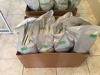 Box filled with multiple bags containing stacked white plastic clothes hangers.