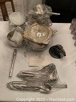 Overview of cookware and utensils wrapped in plastic on table