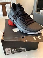 Side view of the black Under Armour Havoc Low shoe sitting on top of a black UA shoe box, showing size 12.5 US label.