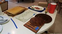 Overview of various wooden charcuterie and cutting boards, glass serving tray, ceramic platters and drink pitcher displayed on a table.