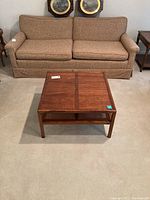 Coffee table in living room setting, placed in front of a brown fabric sofa and between two armchairs, showing top view and side angle.