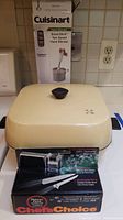 Electric Cuisinart Smart Stick hand blender box and Chilton electric cooker with Chef's Choice knife sharpener on stove.