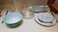 Overview photo of the lot showing all glass measuring cups, bowls, and plates arranged on a countertop.