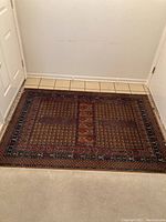View of the entire rectangular wool rug showing pattern and condition.
