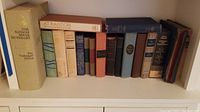 Shelf of 15 hardcover vintage books, various sizes and colors, spines visible, showing titles and authors