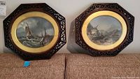 Both framed oval nautical paintings side by side on sofa