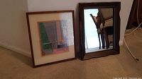Photo showing both wall art and mirror on floor against wall, wood frames visible.