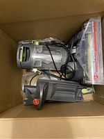 Boxed parts of Hoover Dual Power carpet washer including main unit components with transparent tanks and green handle accents, power cord attached.
