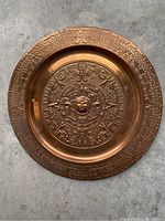 Copper plate with embossed Aztec Calendar design showing detailed symbols and central sun face