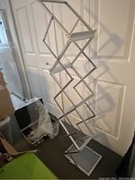 Image showing the document rack fully expanded with diamond shape aluminum frame and clear plexiglass shelves.