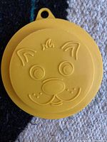 Close-up photo of yellow silicone dog face can cover with embossed dog face design
