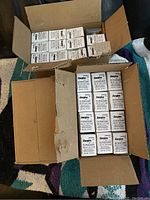 Two open cardboard boxes filled with multiple white boxes containing Energizer CR2032 button cell batteries.