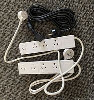 Two white European power strips with attached cords and a black plug conversion cord