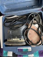 Mastercraft electric hand sander inside open carrying case with sanding disc attached and power cord visible.
