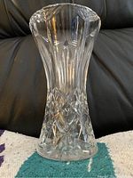 Photo showing a tall clear glass vase with detailed cut and pressed patterns including diamond shapes at the base and vertical cuts along the body.