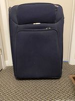 Front view of the large navy soft-sided suitcase showing the front zippered pocket and main compartment zipper.