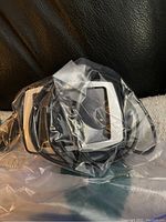 Portable car GPS unit, white and black, sealed in plastic.