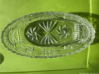 Top view showing detailed pinwheel and floral cut pattern inside the oval crystal bowl; clear and glossy finish with scalloped edges.