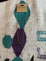 Layered gold-tone necklace on Vitality branded card on a textured fabric