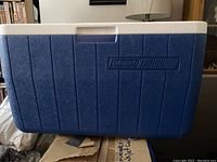 Closed blue and white Coleman cooler showing front side and logo.