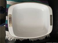 Top-down photo of a large white rectangular roasting pan with metal handles embossed with KitchenAid logo.