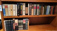 Shelf of various antique and vintage hardcover books including Charles Dickens and others