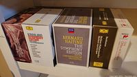 Five classical music box sets on a shelf featuring symphony editions and orchestras/conductors.