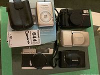 Top and angled view showing five cameras and leather case