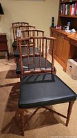 Three chairs in a row showing wood frames and black seat cushions