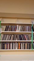 Shelf with multiple rows of CDs, various artists and albums, mostly rock genre.