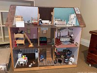 Front view of full three-story dollhouse showing six rooms with furniture and miniatures