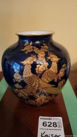 Front view of the Kaiser vase showing two roosters and floral patterns in gold on a deep blue background, with gold rim detail.