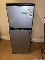 Front view of Magic Chef mini fridge showing top freezer and bottom fridge with stickers.