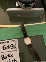 Top view of Birks ladies watch showing rectangular gold-tone case, white dial, and brown leather band.