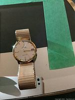Front view of Mido men's Ocean Star watch on Speidel gold-tone metal expansion band, showing dial, date and day calendar function, and overall wearable condition with slight signs of use.