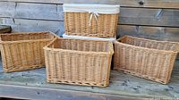 Five wicker baskets grouped together on a wooden surface, showing both lined and unlined varieties.