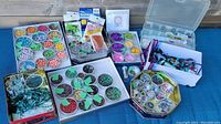 Wide photo showing the entire bead lot containing multiple boxes and containers of beads, strands, and beading supplies on a blue surface.