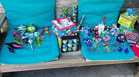 Overall view of the collection including ornaments and storage tote, spread on a teal blue cushions of outdoor furniture.