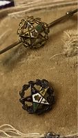 Two lapel pins featuring five-pointed stars surrounded by laurel wreaths, one mounted on horizontal bar pin back, the other standalone. Pins have multiple colored enamel sections and metallic laurel details.