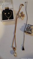 Three jewelry sets including a faux diamond set, pearl and faux diamond set, and a pewter teddy bear set with necklace, earrings, and trinket box pendant.