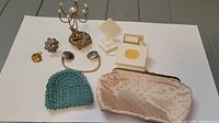 Overview of collection featuring clutch, beaded coin purse, sweater clip, metal pins, jewelry holder stand, and two ring boxes