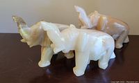 Side angle view of three marble elephant figurines showing color and size differences